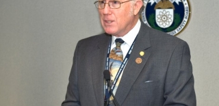 Image of a man wearing a dark gray suit jacket and speaking at the 2010 Victor Stello Junior award presentation